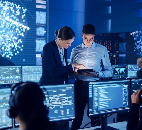 Project Manager and Computer Science Engineer Talking while Using A Digital Tablet Computer. Telecommunications Company System Control and Monitoring Office Room with Working Specialists.